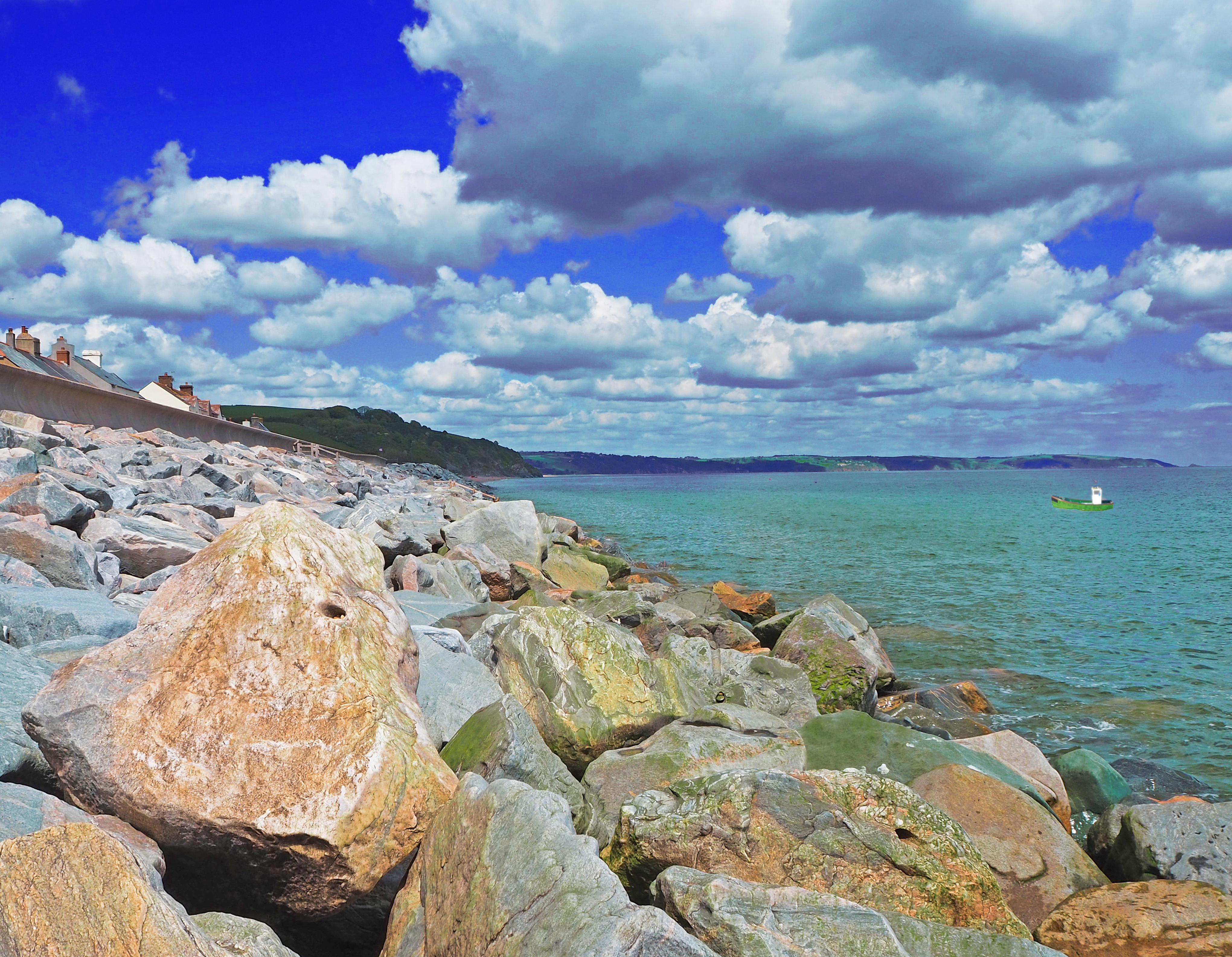 big boulders on beach with blue sea and boat