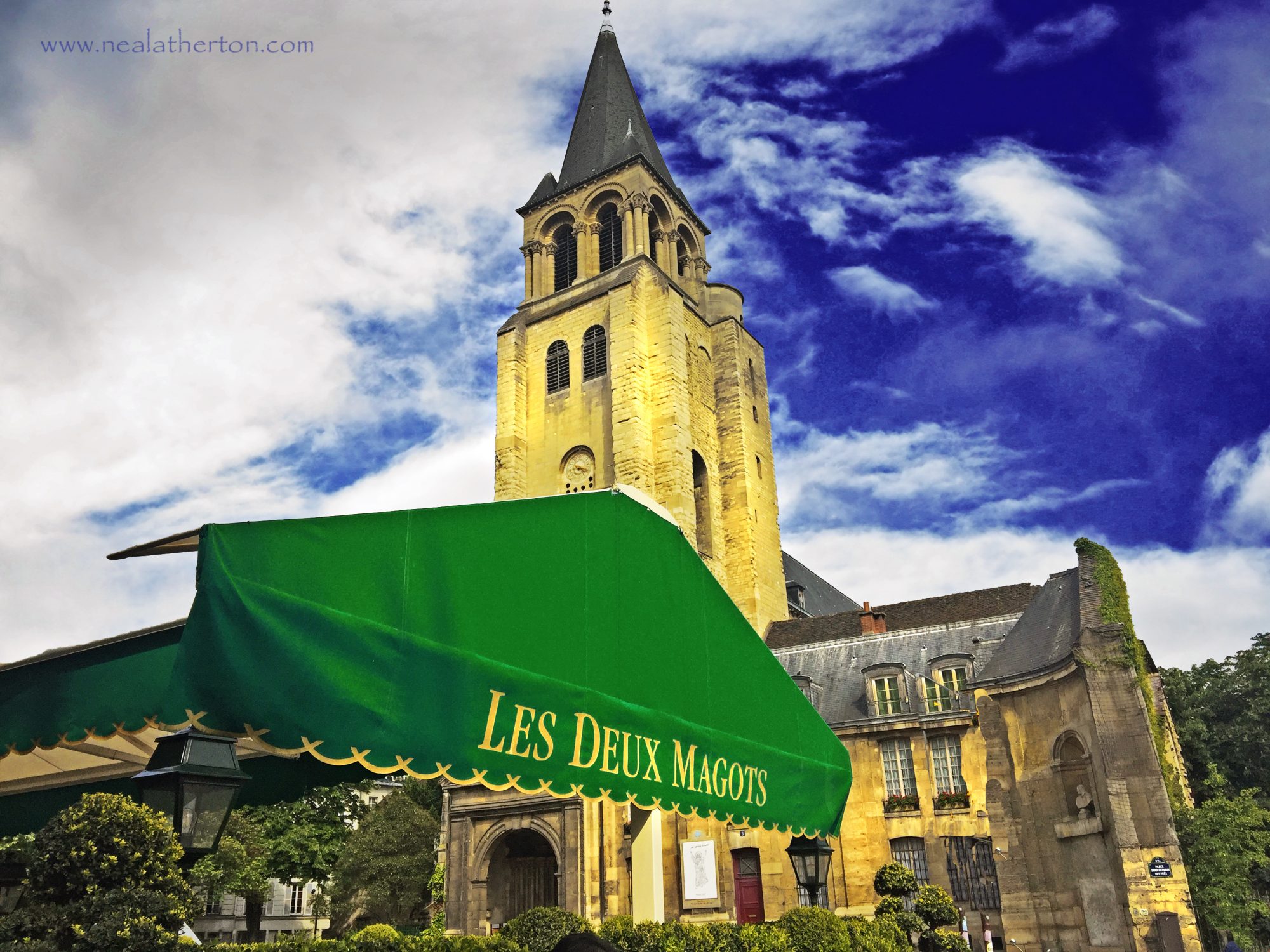 cafe awning over terrace in city with church and tall steeple tower