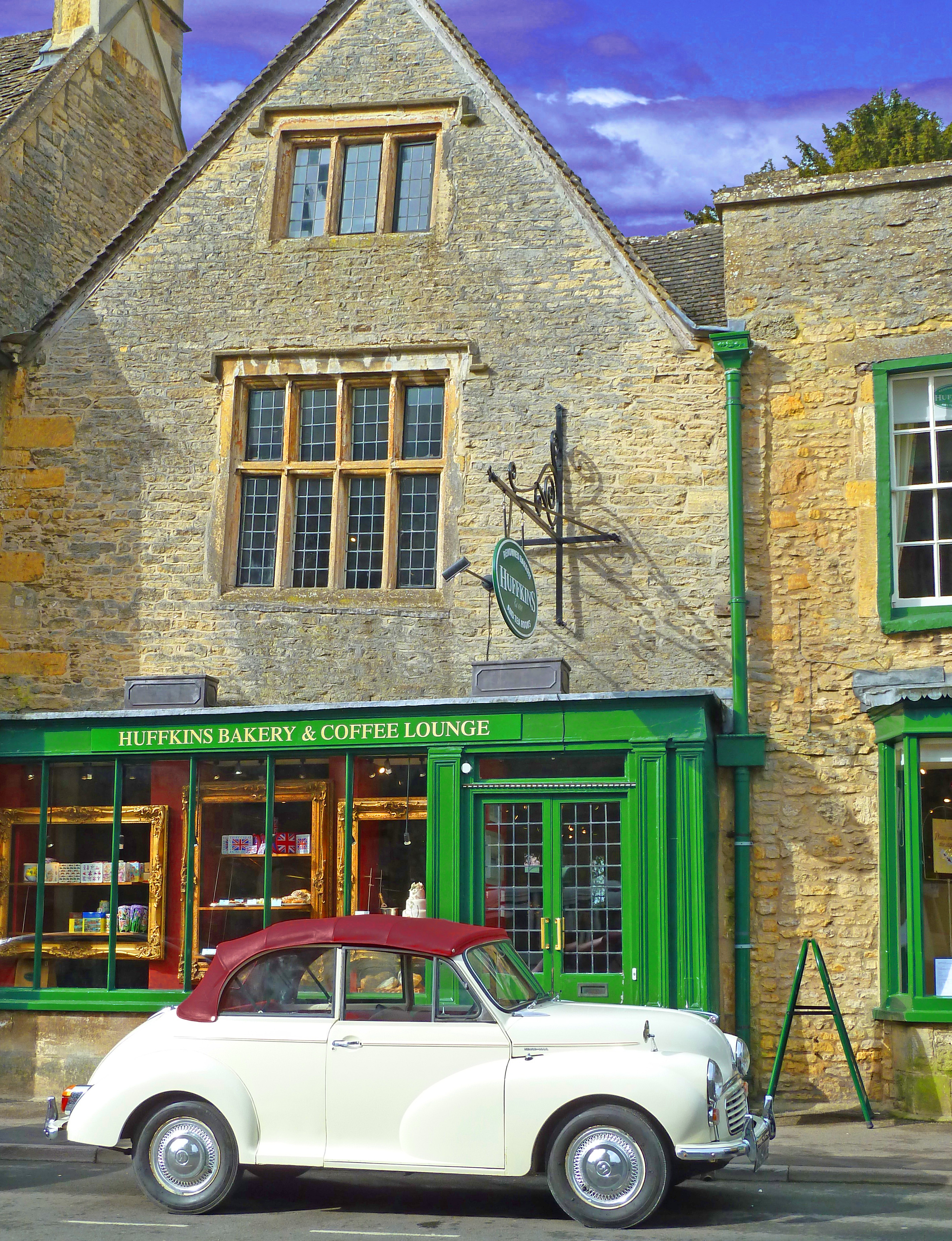 White morris minor car in front of aancient shop with bakery and grren frontage