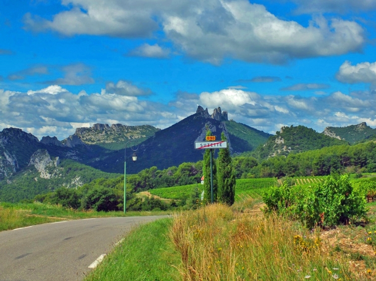 Road and sign with mountains and vinyards and blue sky with clouds