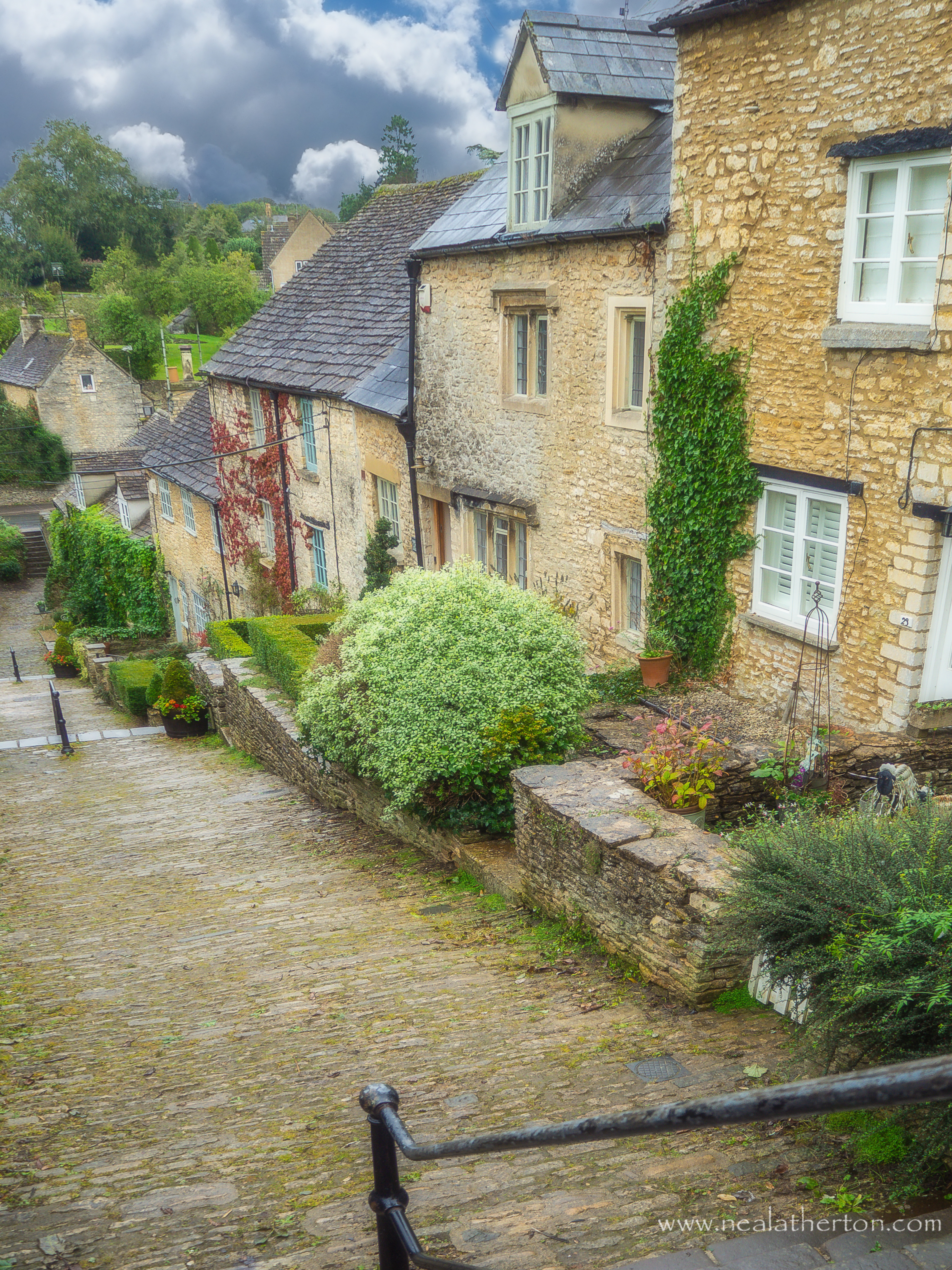 metal rail on steps with cobbles with houses and shrubs