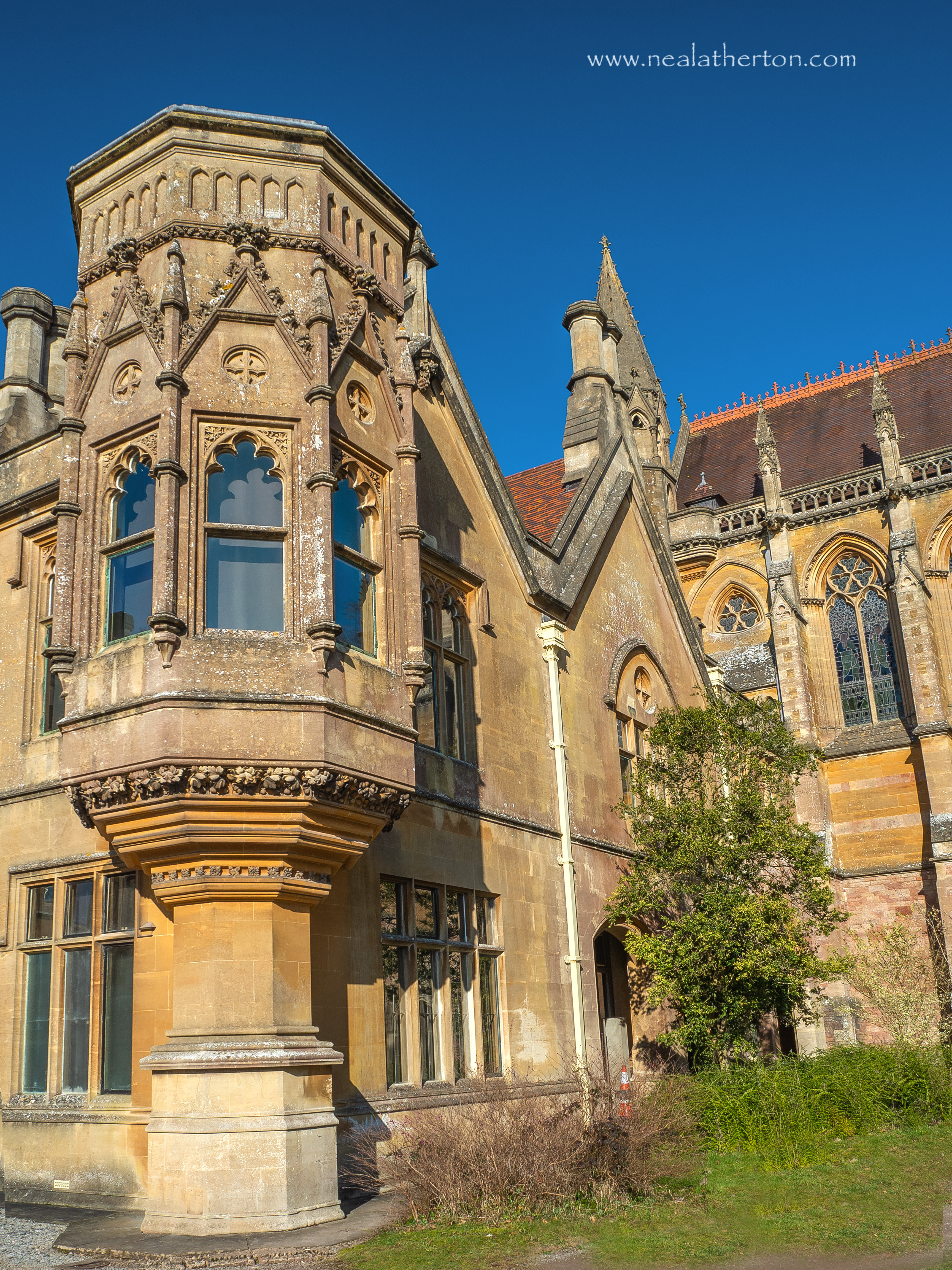corner rooms of stone house with chapel and trees in front under blue sky