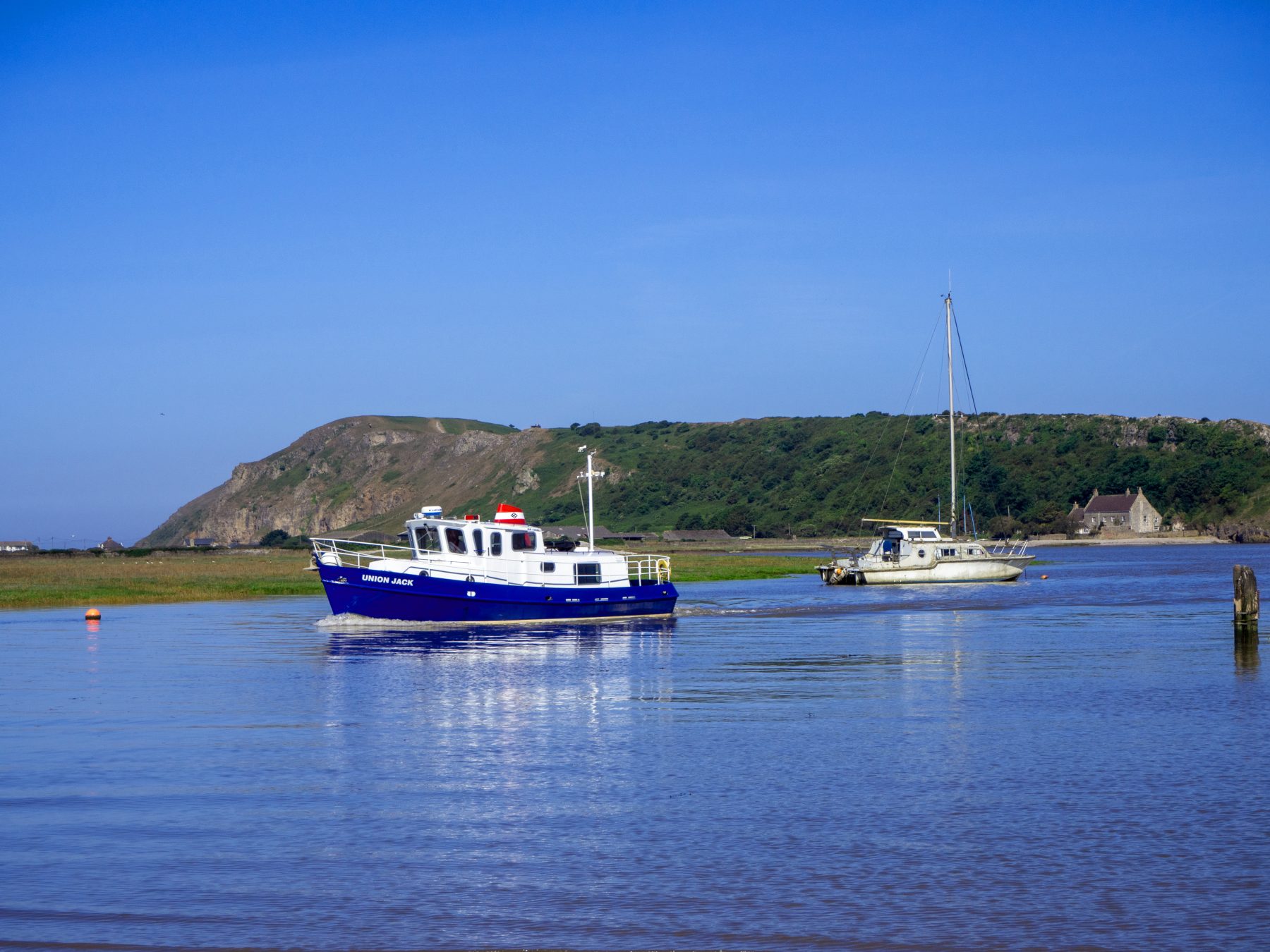 pleasure boat and yacht on high tide river with island and blue sky