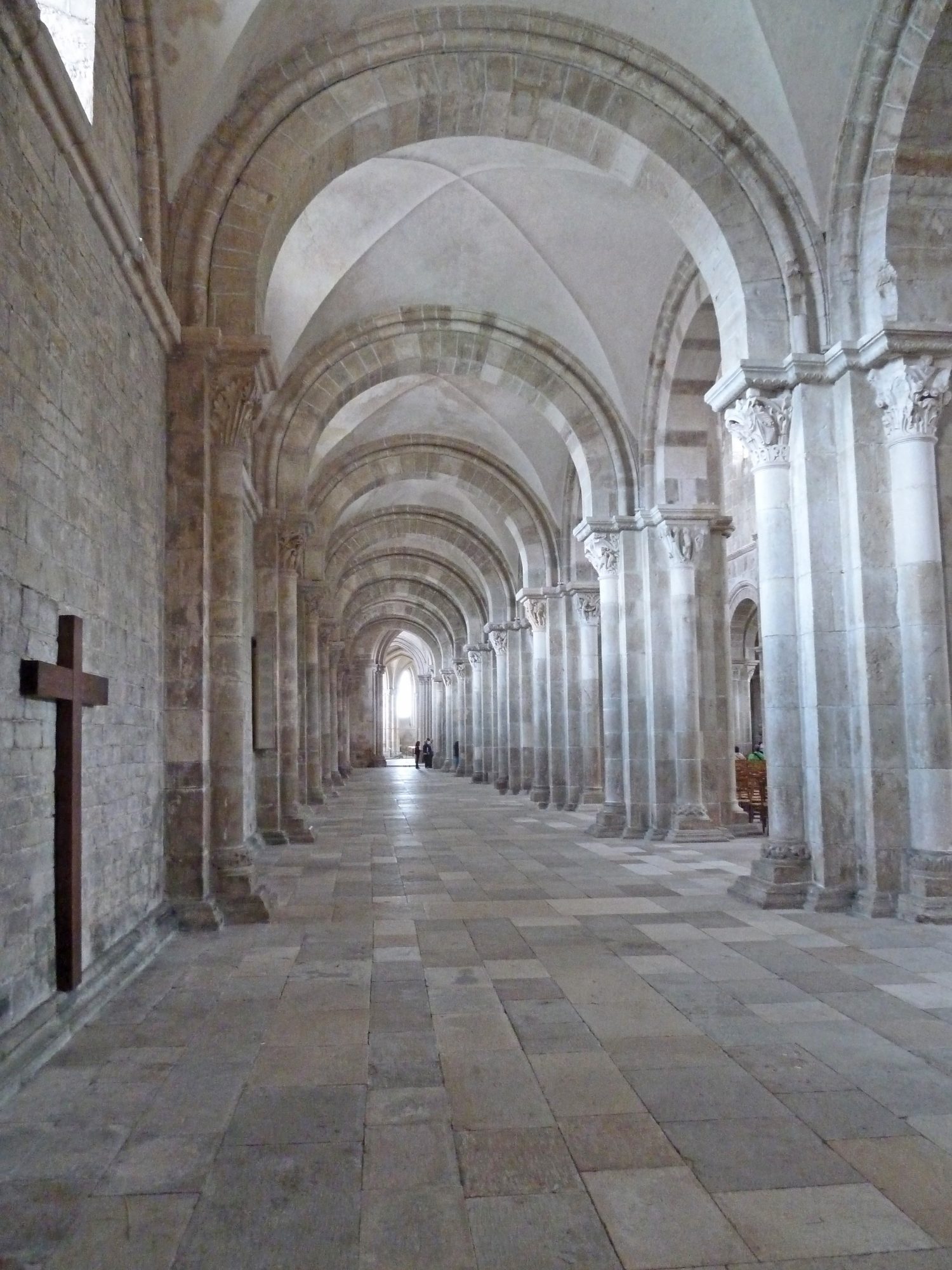 stone arch pillars in cathedral with stone floor and cross