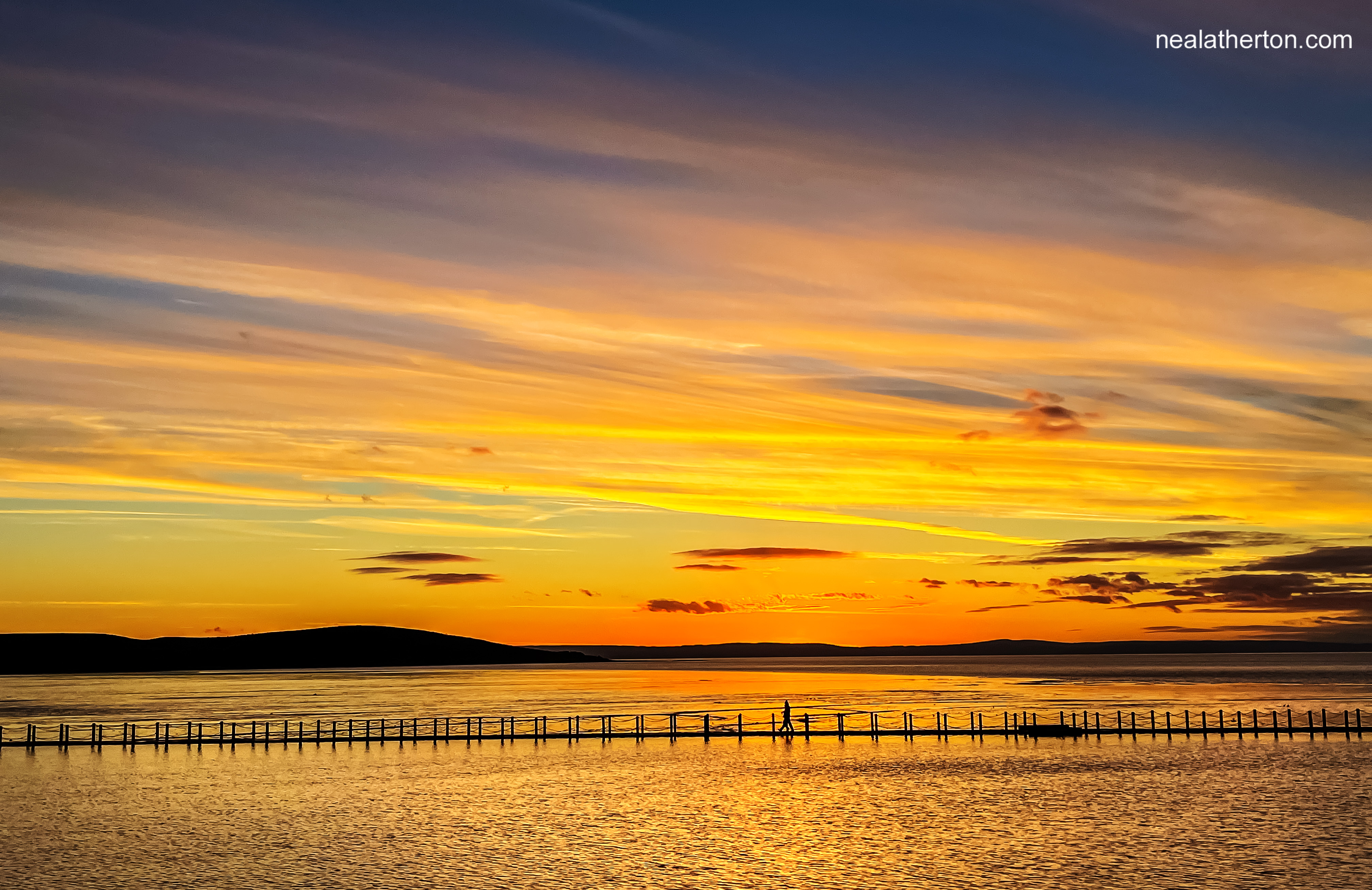 Sun has just set over Britol Channel giving ren, orange,blue sky behind the Marine lake walkway North Somerset