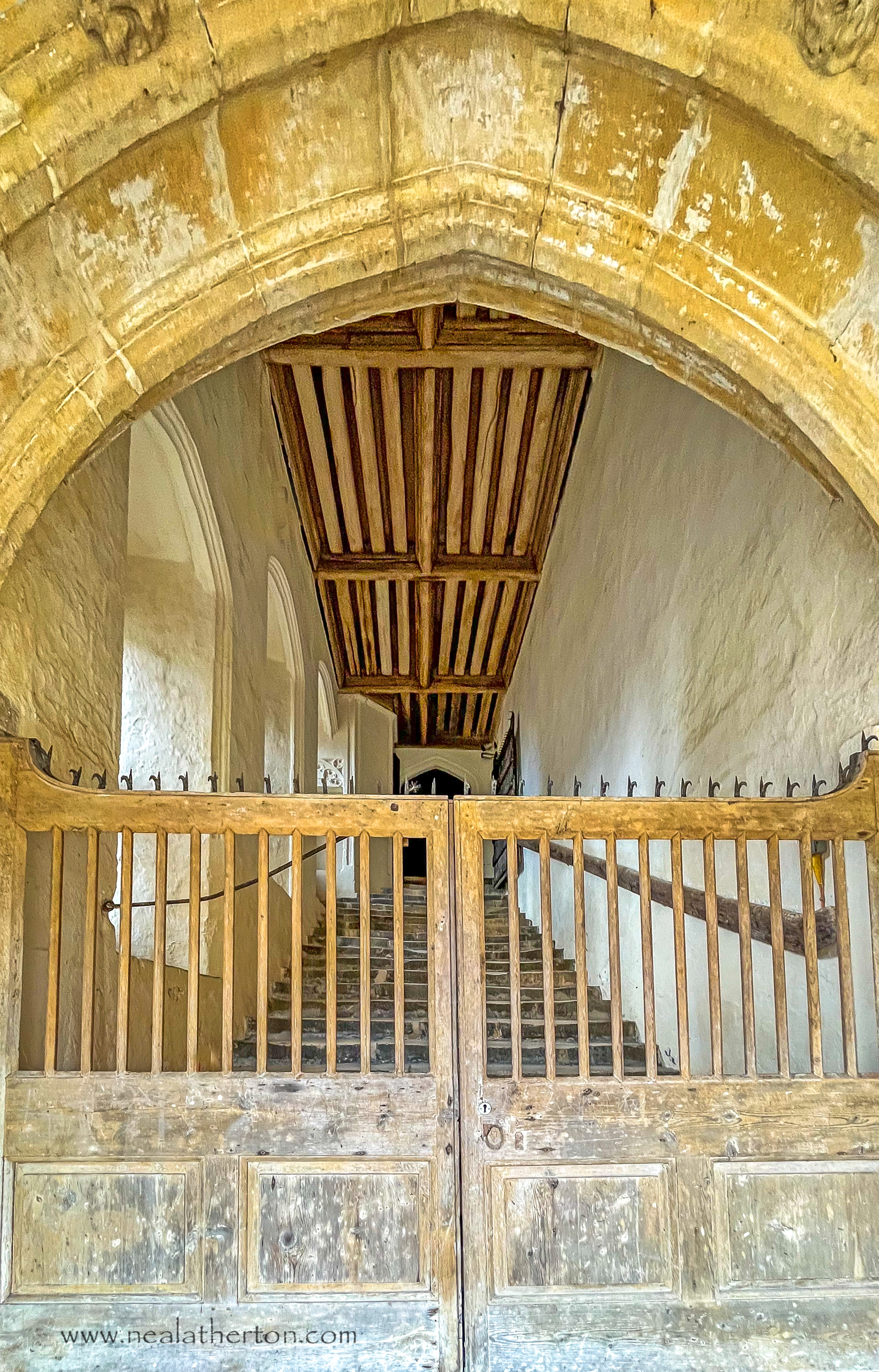 Wooden ancient gate in front of stone medieval steps under a stone archway