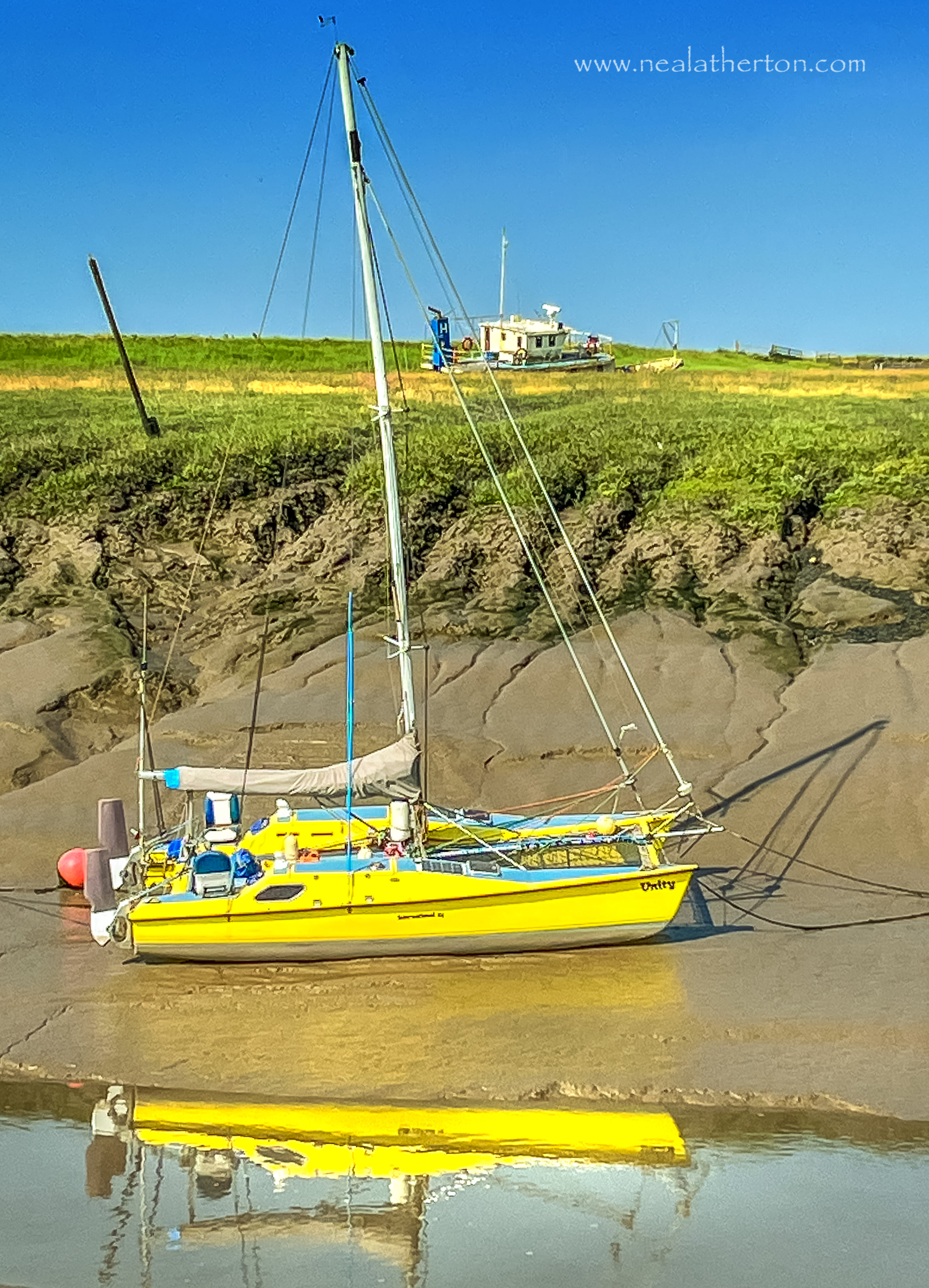 Boat reflected in estuary water with old boat in distant field somerset