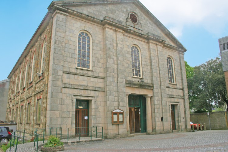 Church in cornish stone with notice board and front doors with blue sky